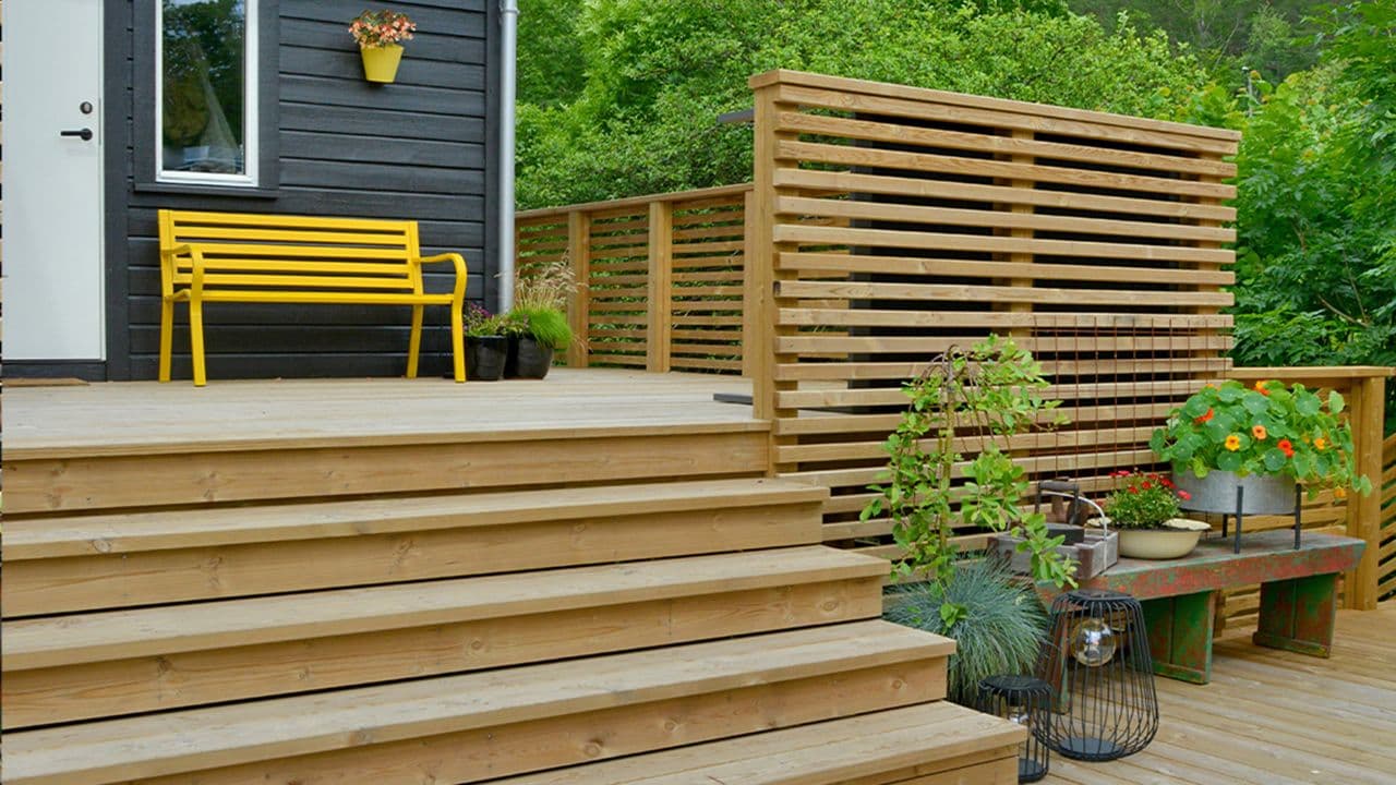 Terrasse med trapp og rekkverk laget av spiler.