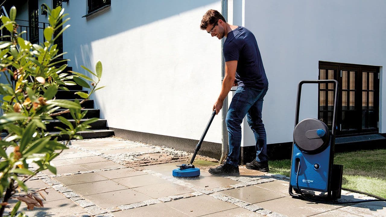 En mann vasker ute med Nilfisk produkt