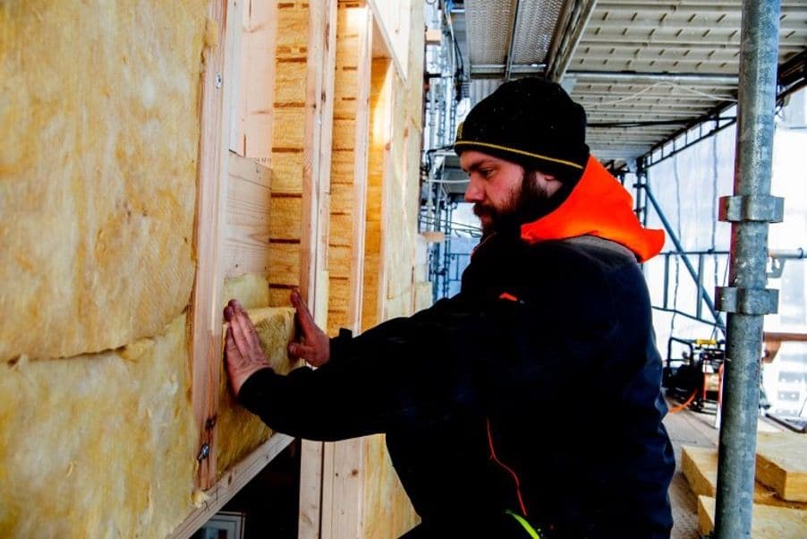 en mann som legger isolasjon på et hus