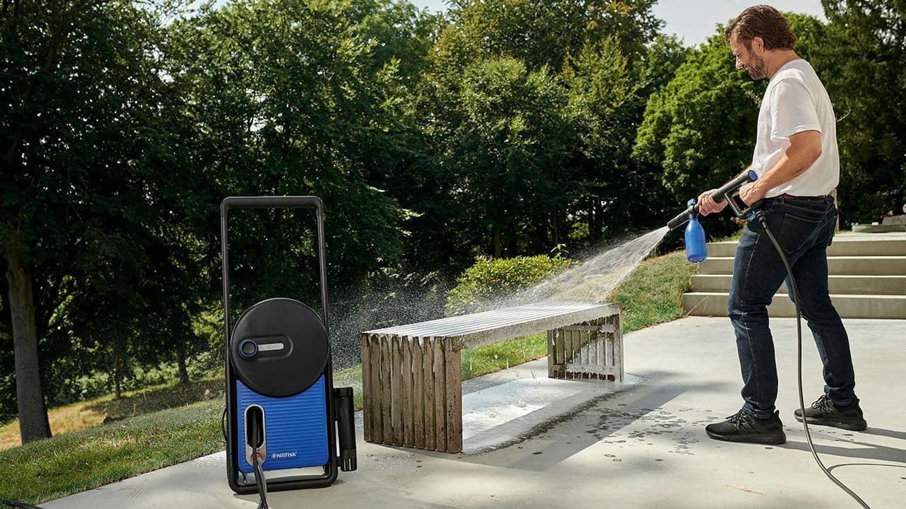En mann vasker ute med et Nilfisk produkt