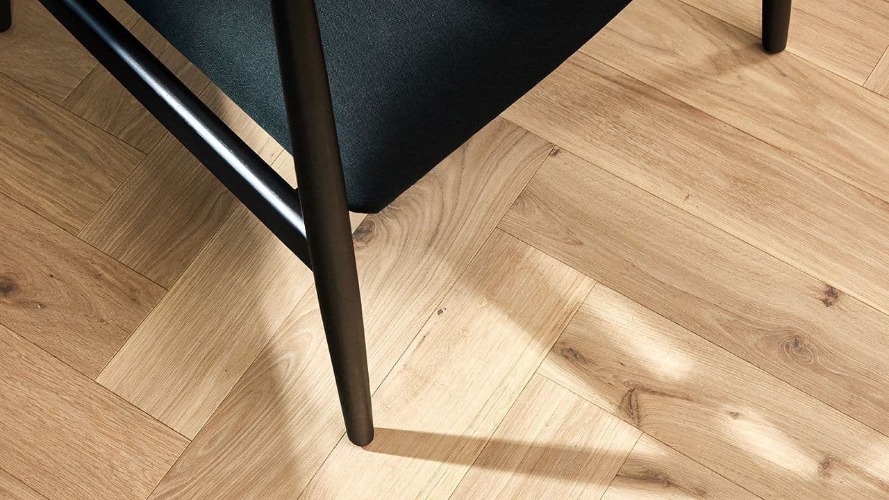 Nærbilde av fiskebeinsparkett fra Boen i stue med svart lenestol.