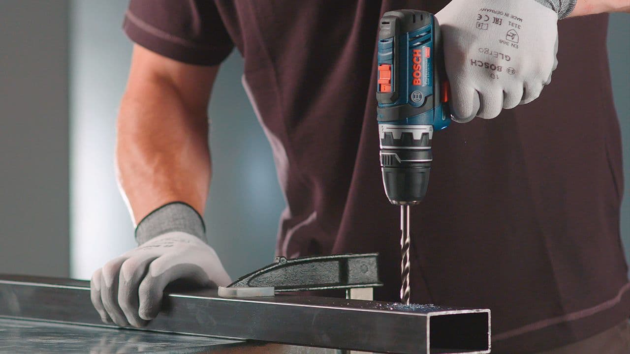 Mann som borer i stål med en drill.