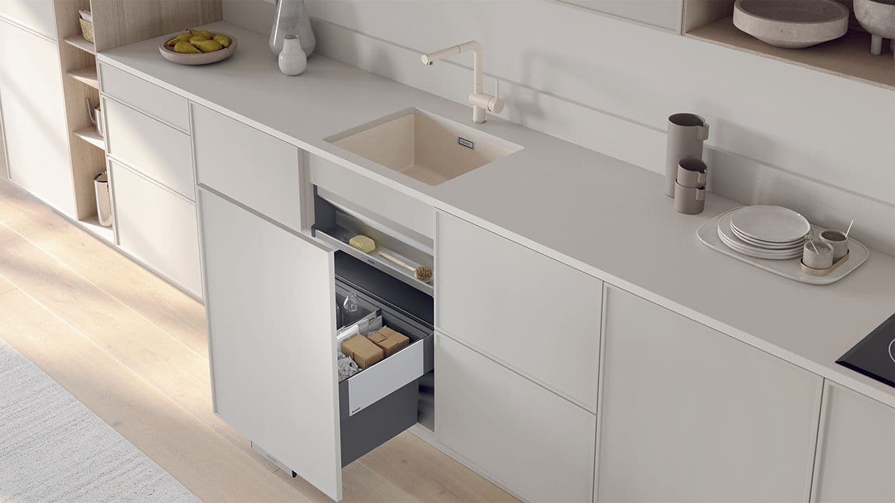 Lyst kjøkken med lys benkeplate, matchende kjøkkenvask og blandebatteri og smart søppelsortering.