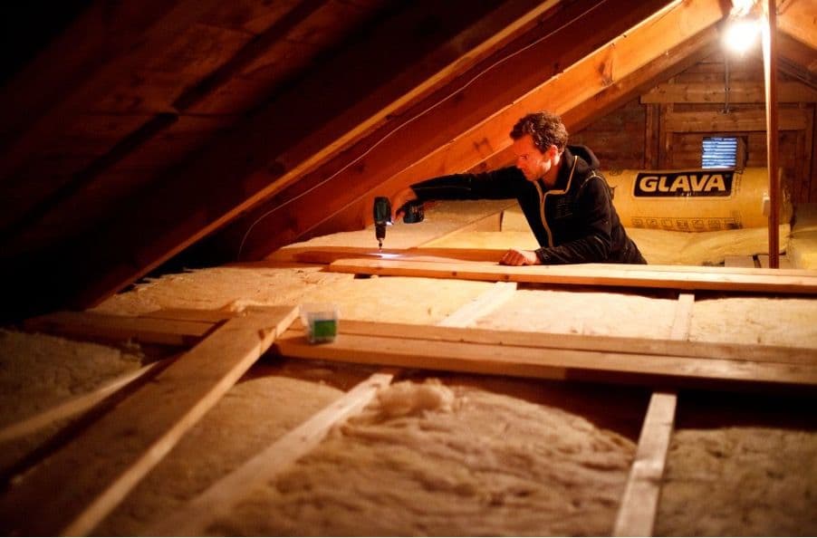 en mann som legger isolasjon på et loft