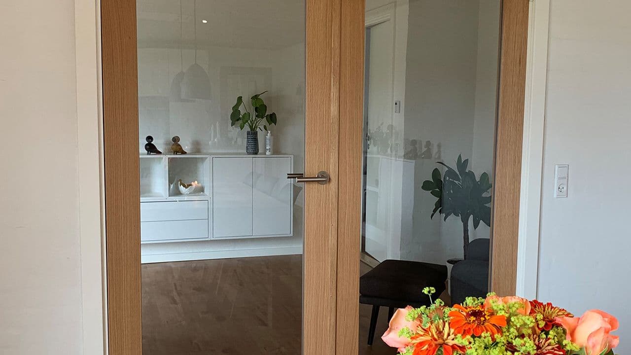 Dobbel innerdør i glass fra kjøkken til stue i lyst treverk.