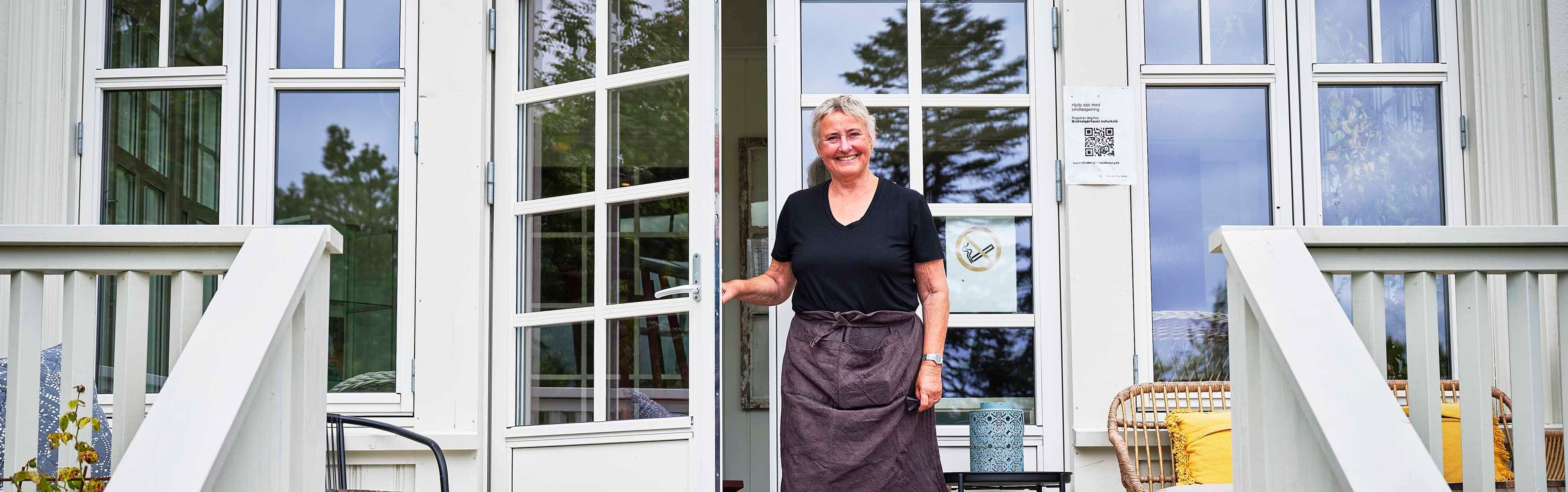 Kvinne er på vei ut av en klassisk balkongdør med sprosser om våren.