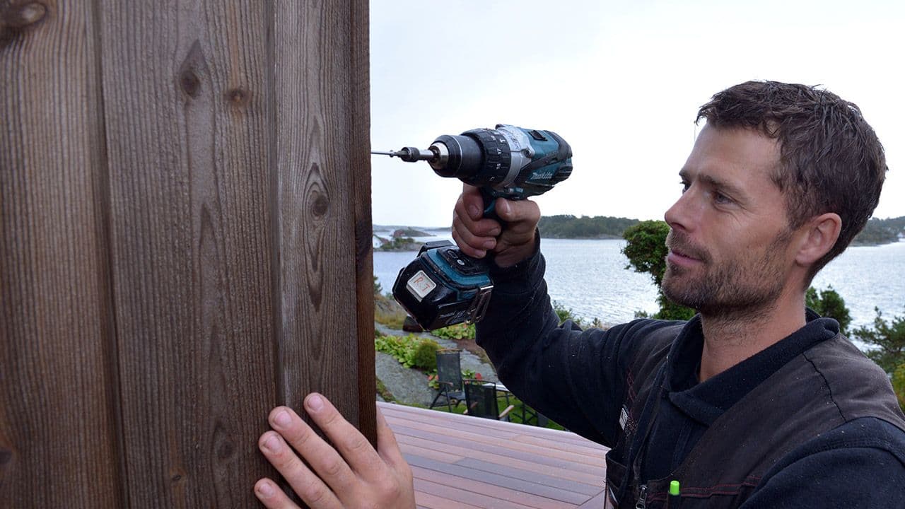 Mann som skrur inn fasadeskruer med drill.