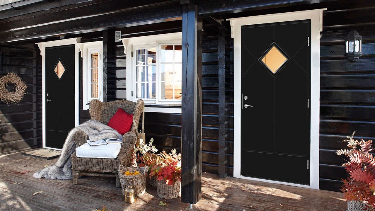 Klassisk tømmerhytte med svart hyttedør.