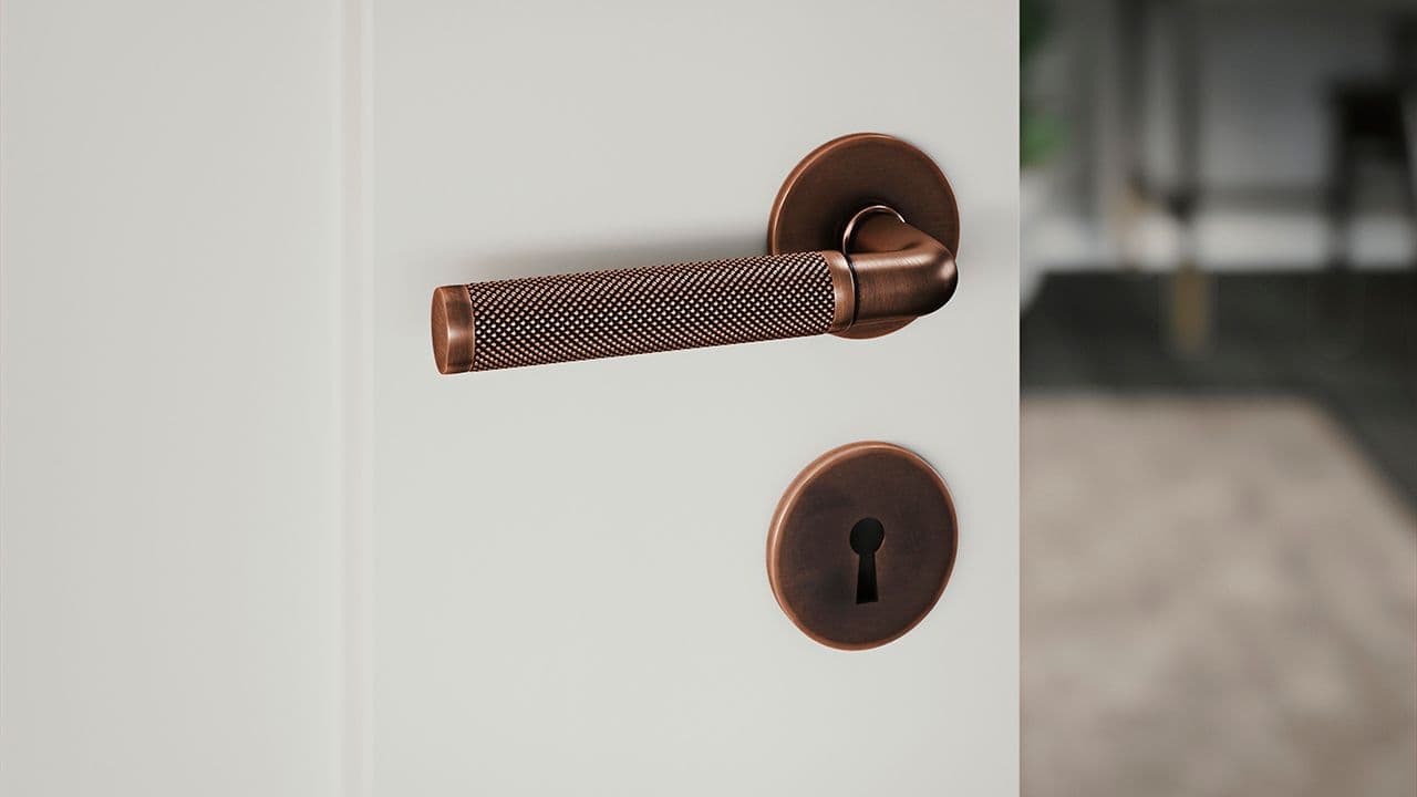 Dørhåndtak innerdør i kobber på hvit dør.