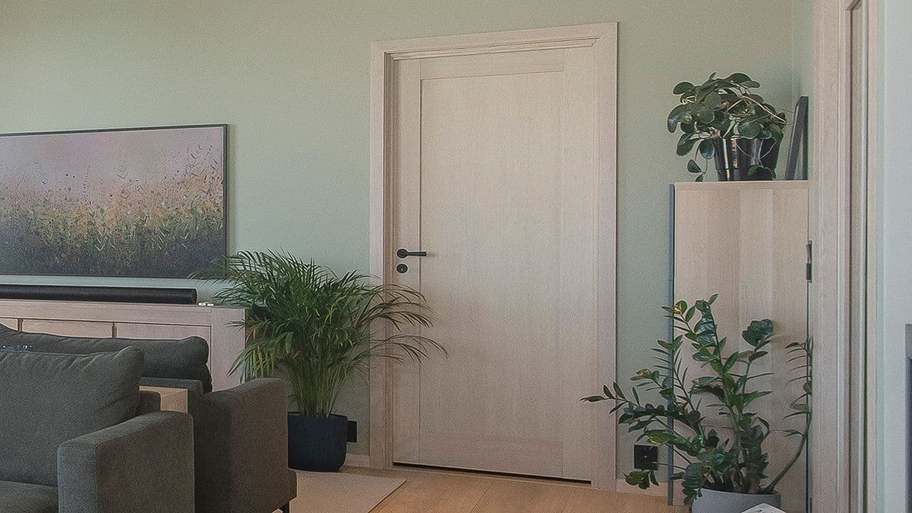 Stue med eik innerdør mes sort håndtak og vrider.